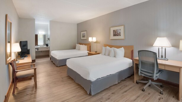 A hotel room with two beds, a desk with a chair, a TV, and two lamps. - Best Western Inn (Goshen)
