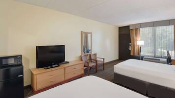 A hotel room with a bed, a TV, a desk with a chair, a mirror, and a window with curtains.