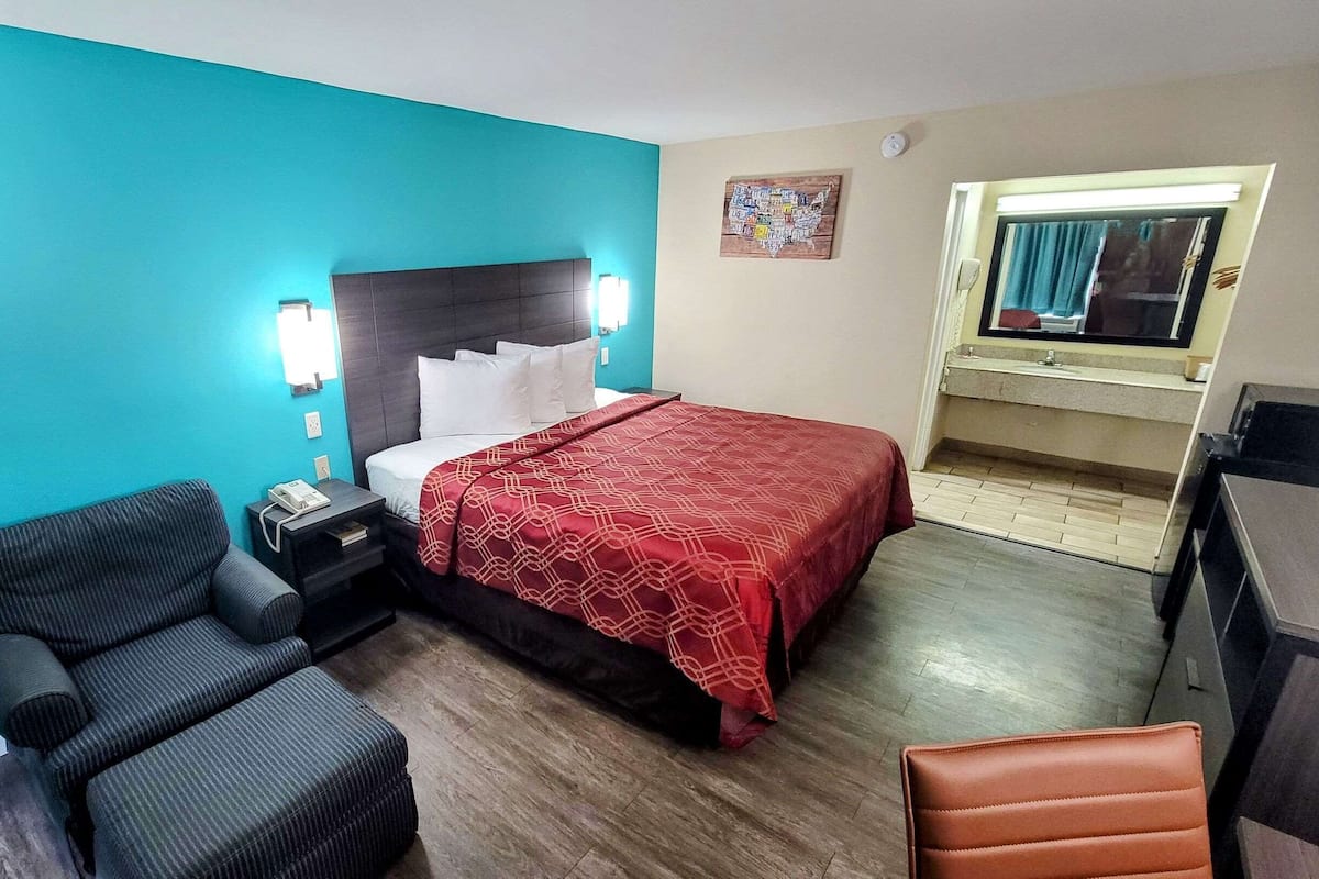 A hotel room with a bed, a desk, a chair, and a small table.