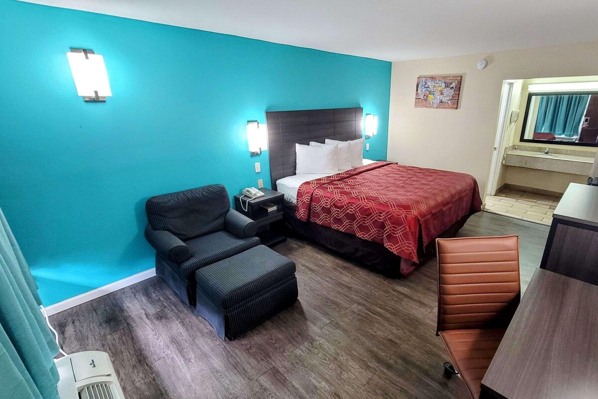 Una habitación de hotel con cama, escritorio, sillón, sofá y una pequeña mesa.