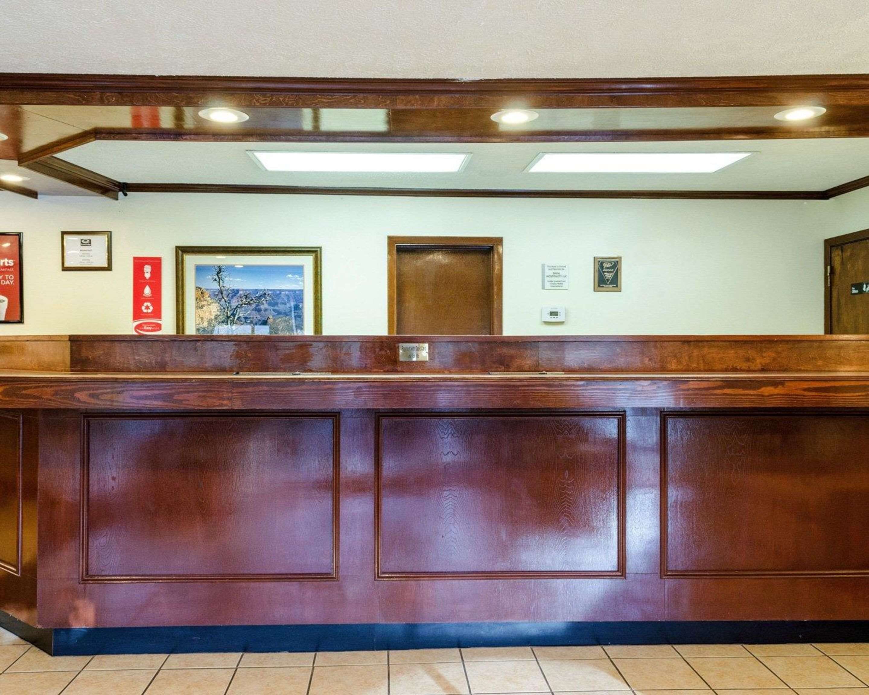 A reception desk with a wooden finish, a framed picture on the wall, and a door with a plaque.