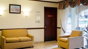 Un vestíbulo de hotel con una mesa de recepción, un cuadro enmarcado en la pared y una puerta con la leyenda “Solo personal”.