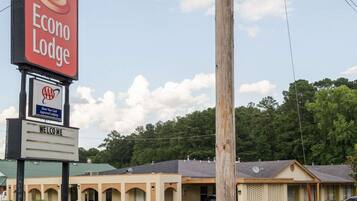 A motel named Econo Lodge with a signboard, a 'Show Your Card' AAA Approved Lodging sign, and a 'Welcome' sign.