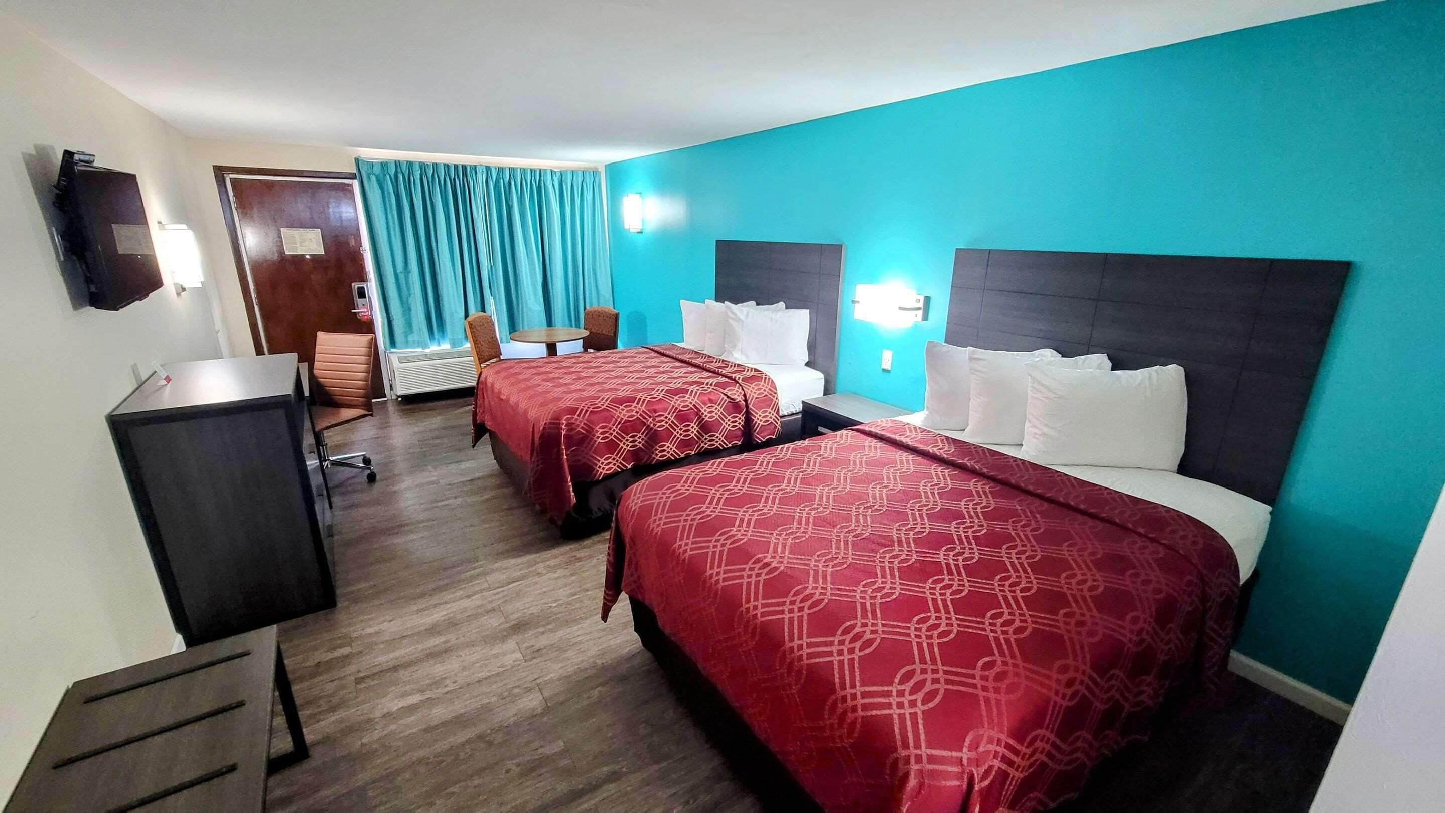 Een hotelkamer met twee bedden, een bureau, een stoel en een televisie.