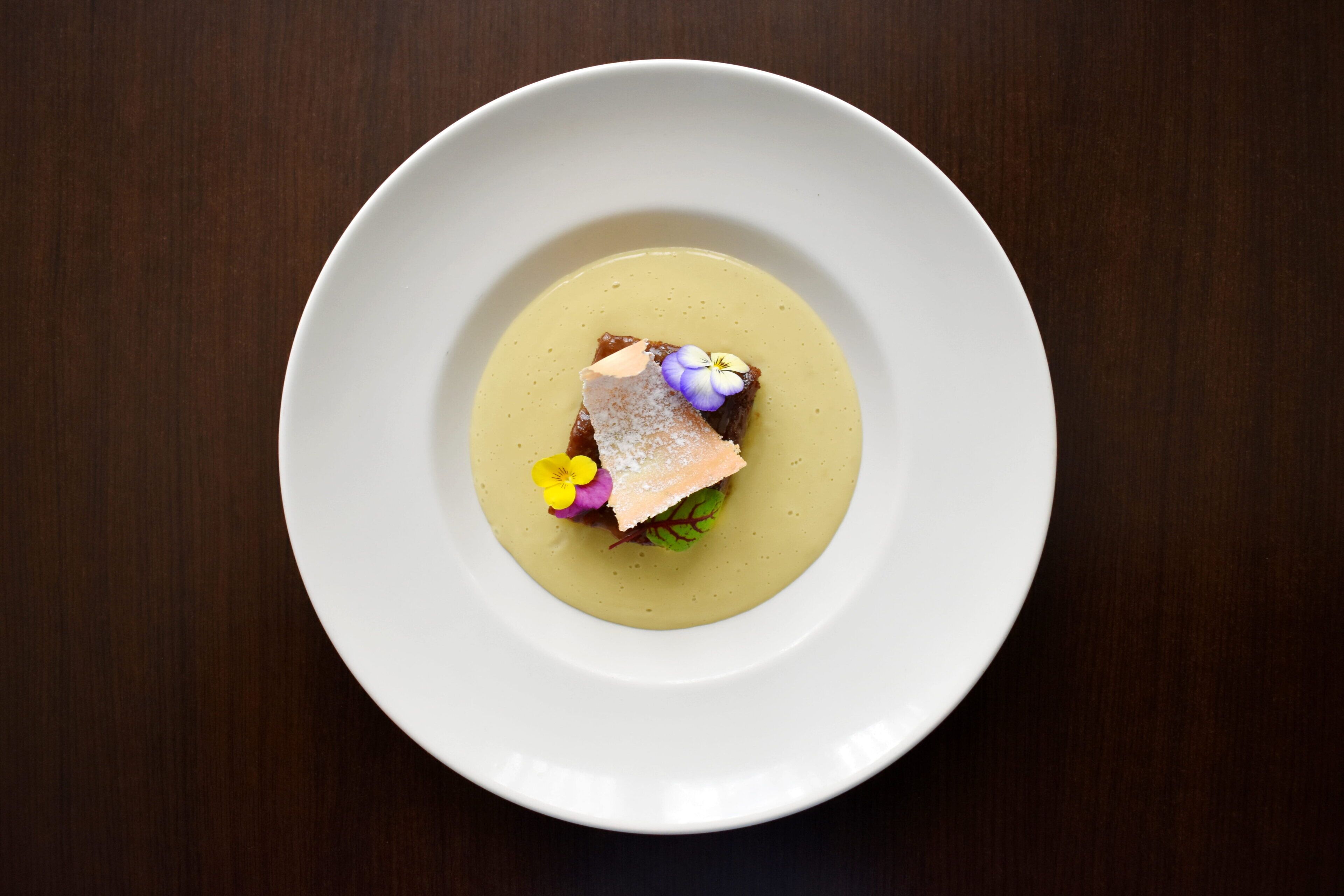 A white plate with a dessert on a dark wooden table.