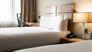 Een hotelkamer met twee bedden, een bureau met een lamp, een stoel en een telefoon.