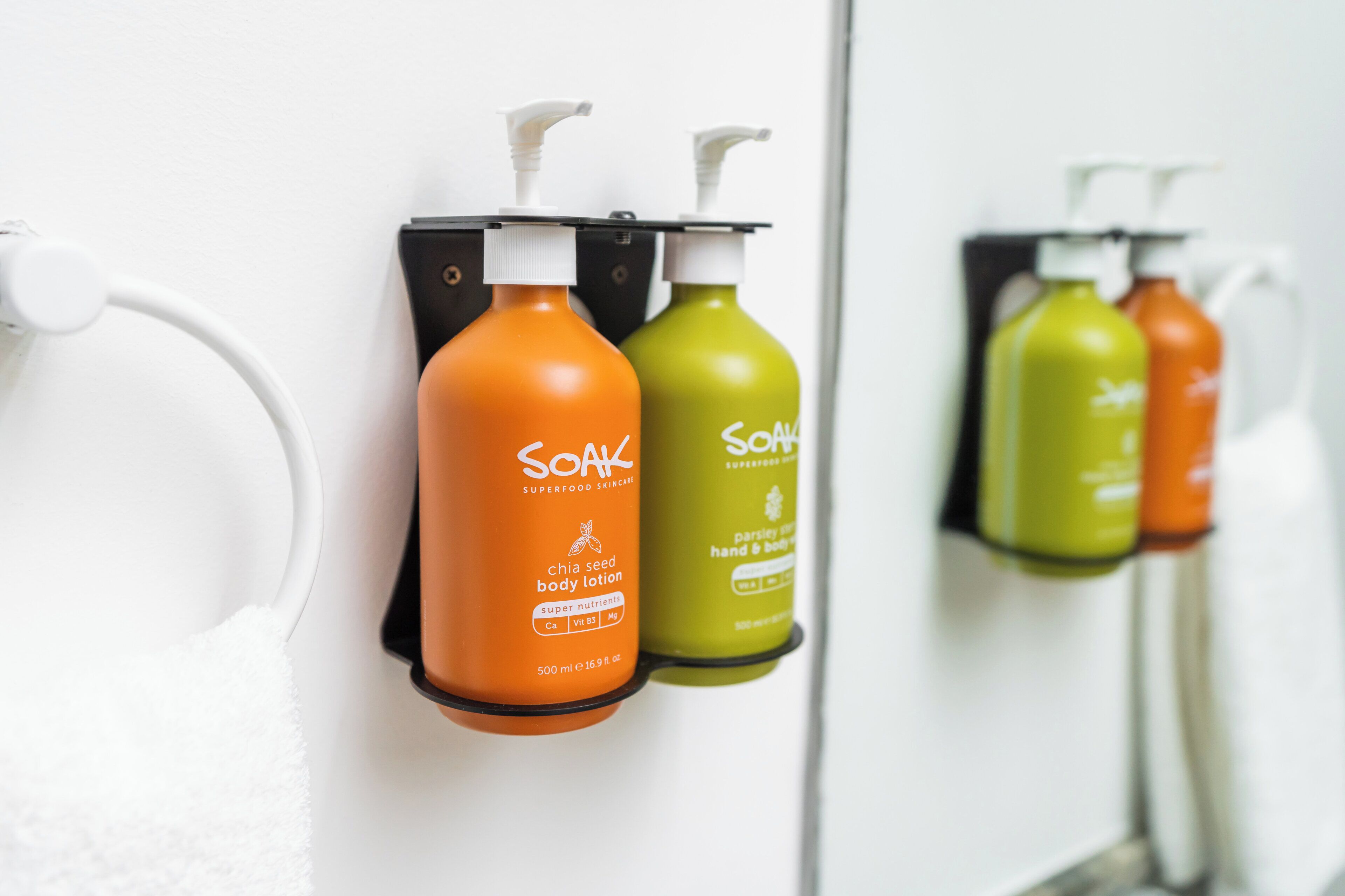 A bathroom with a hand dryer and two bottles of soap.