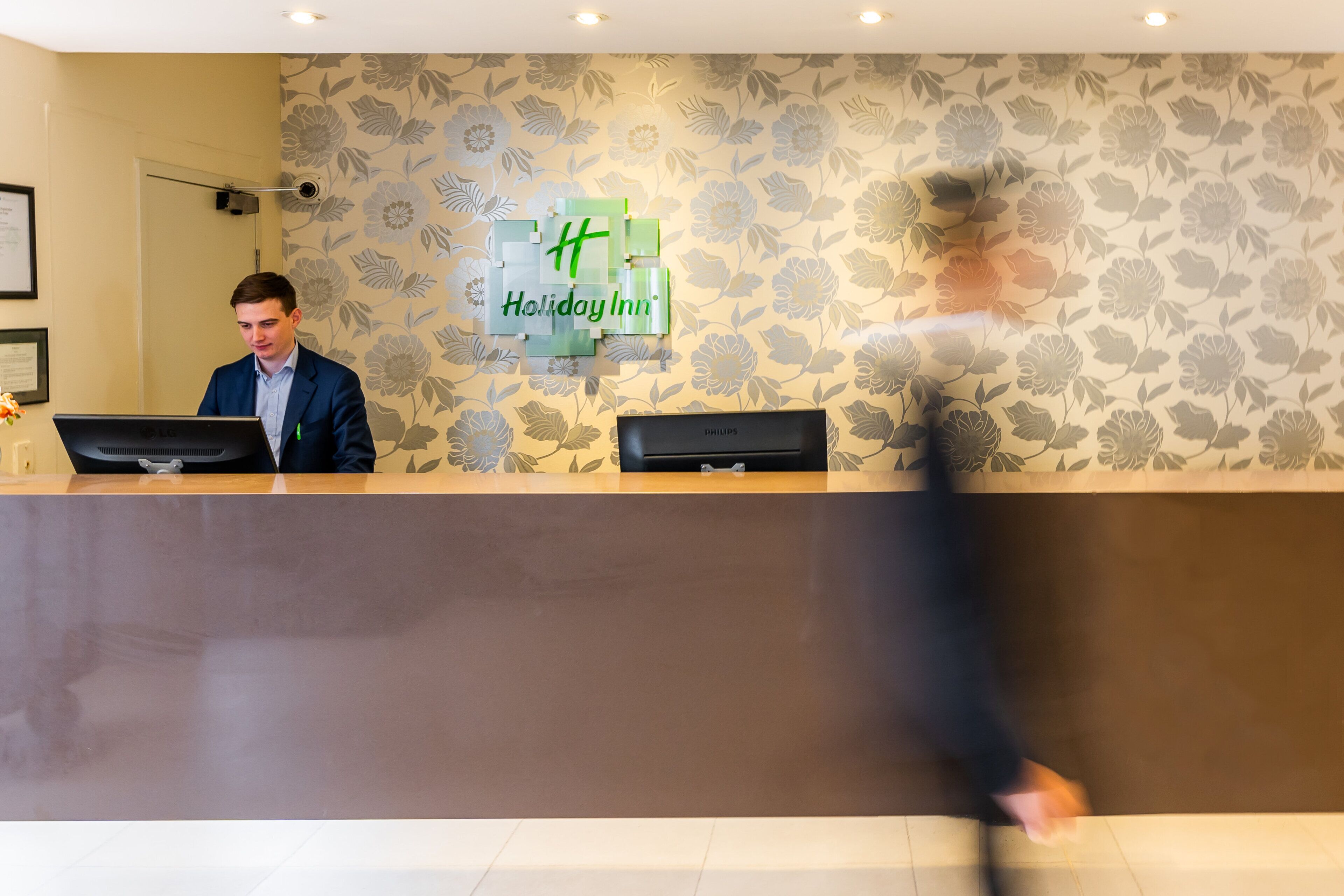 Una recepción con el letrero de Holiday Inn, una lámpara de escritorio y una computadora.
