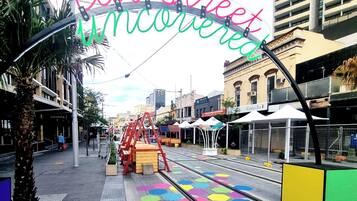 A street with colorful hexagonal tiles, a red swing set, and a sign that reads "eat street uncensored".