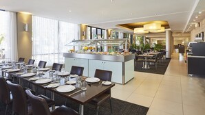 Een moderne eetruimte met een buffet, comfortabele zitplaatsen en uitzicht op de omgeving.