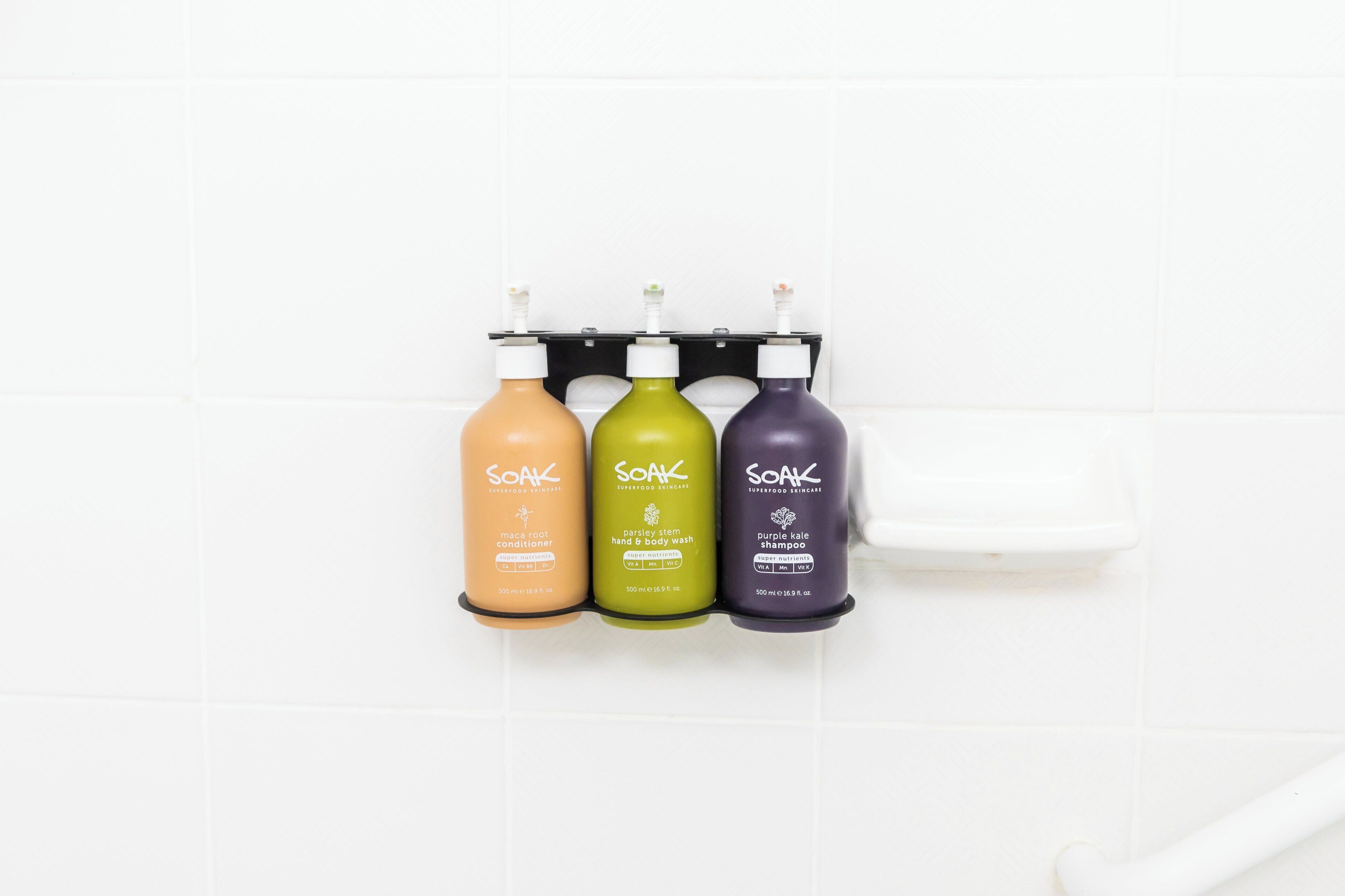 Three bottles of Soak Superfood Skincare products on a white tiled wall.