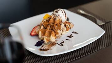 A plate of waffles with chocolate drizzle and a scoop of ice cream.