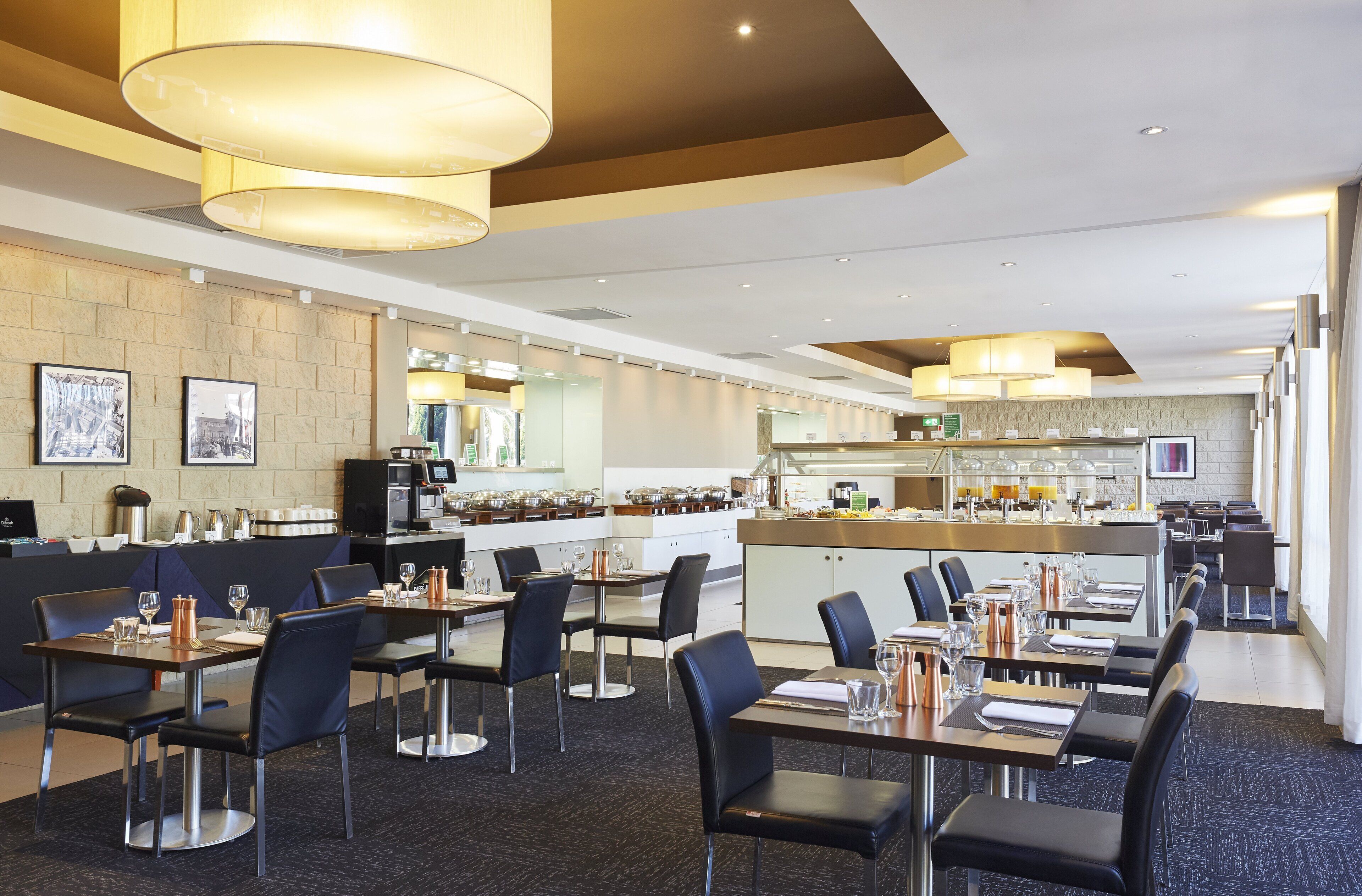 Un ristorante moderno con un lungo bancone, sedie nere e un'area bar.