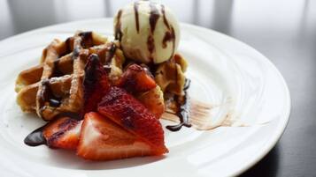 Un piatto con waffle, fragole e una pallina di gelato.