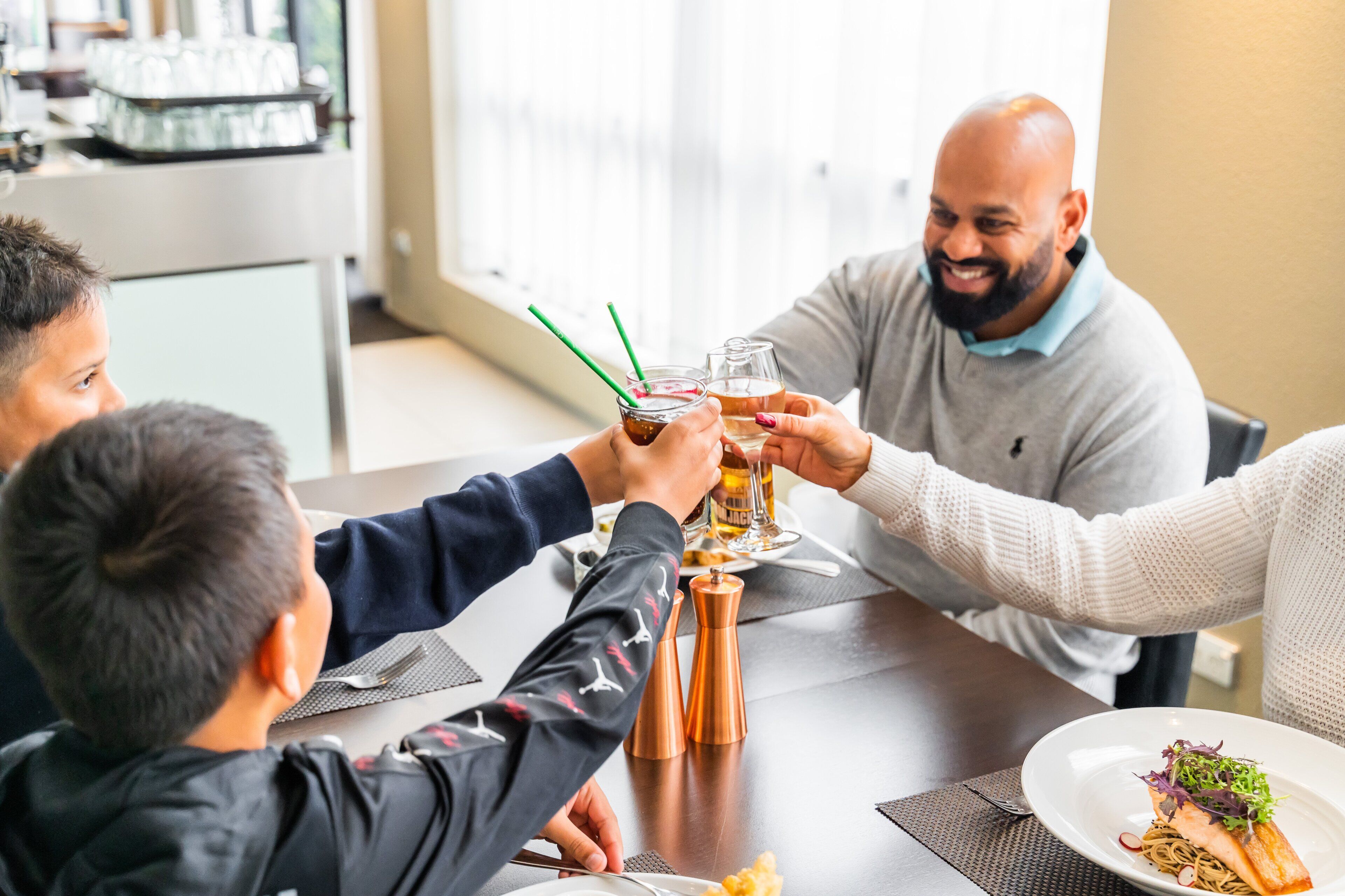 Un grupo de personas brindando alrededor de una mesa con comida delante.