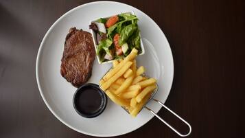 A plate with a steak, a small salad, and French fries.