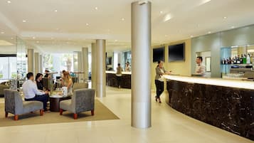 Un moderno vestíbulo de hotel con mostrador de recepción, zona de estar y pilares grandes.