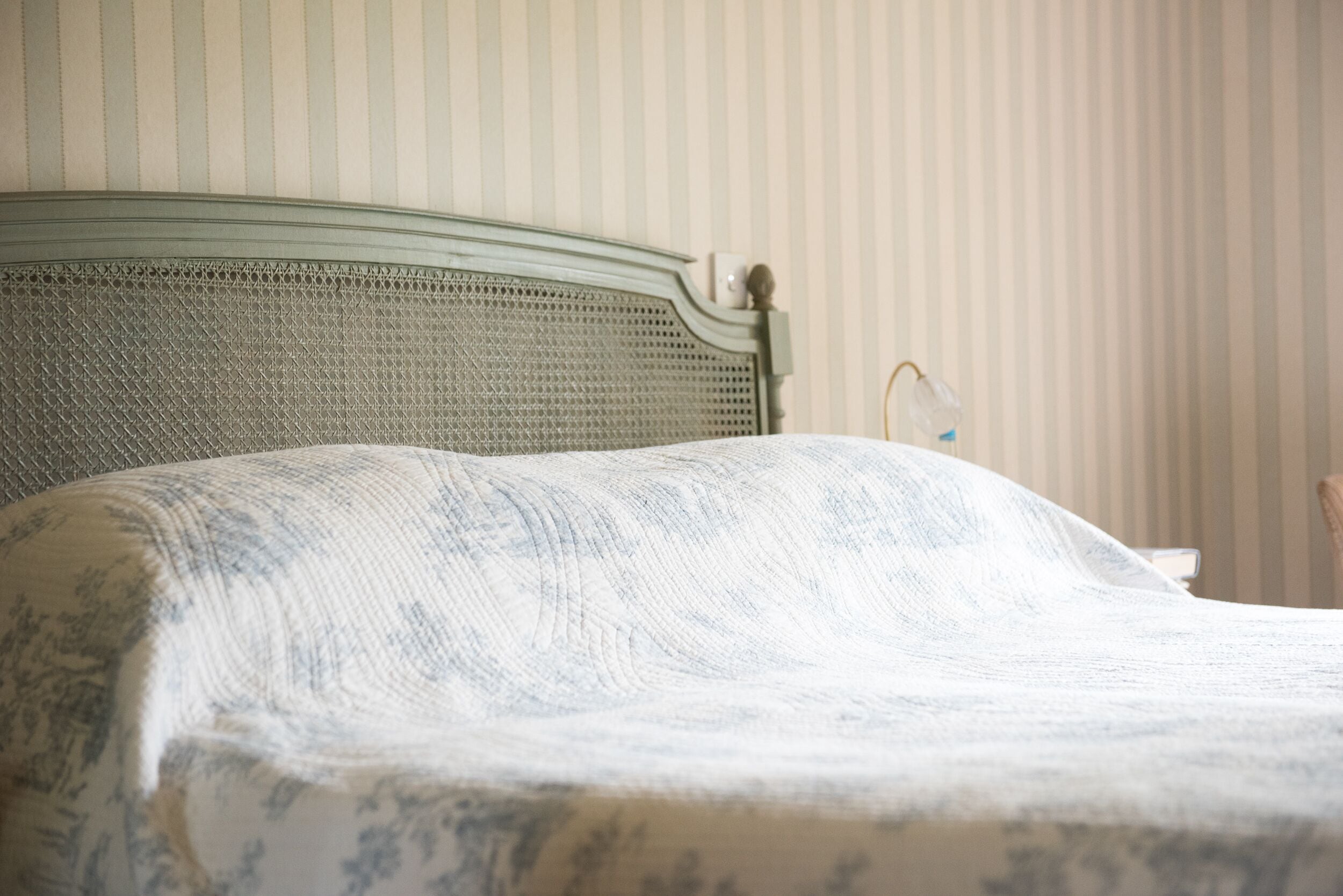 A bed with a patterned bedspread and a headboard with a decorative finial.