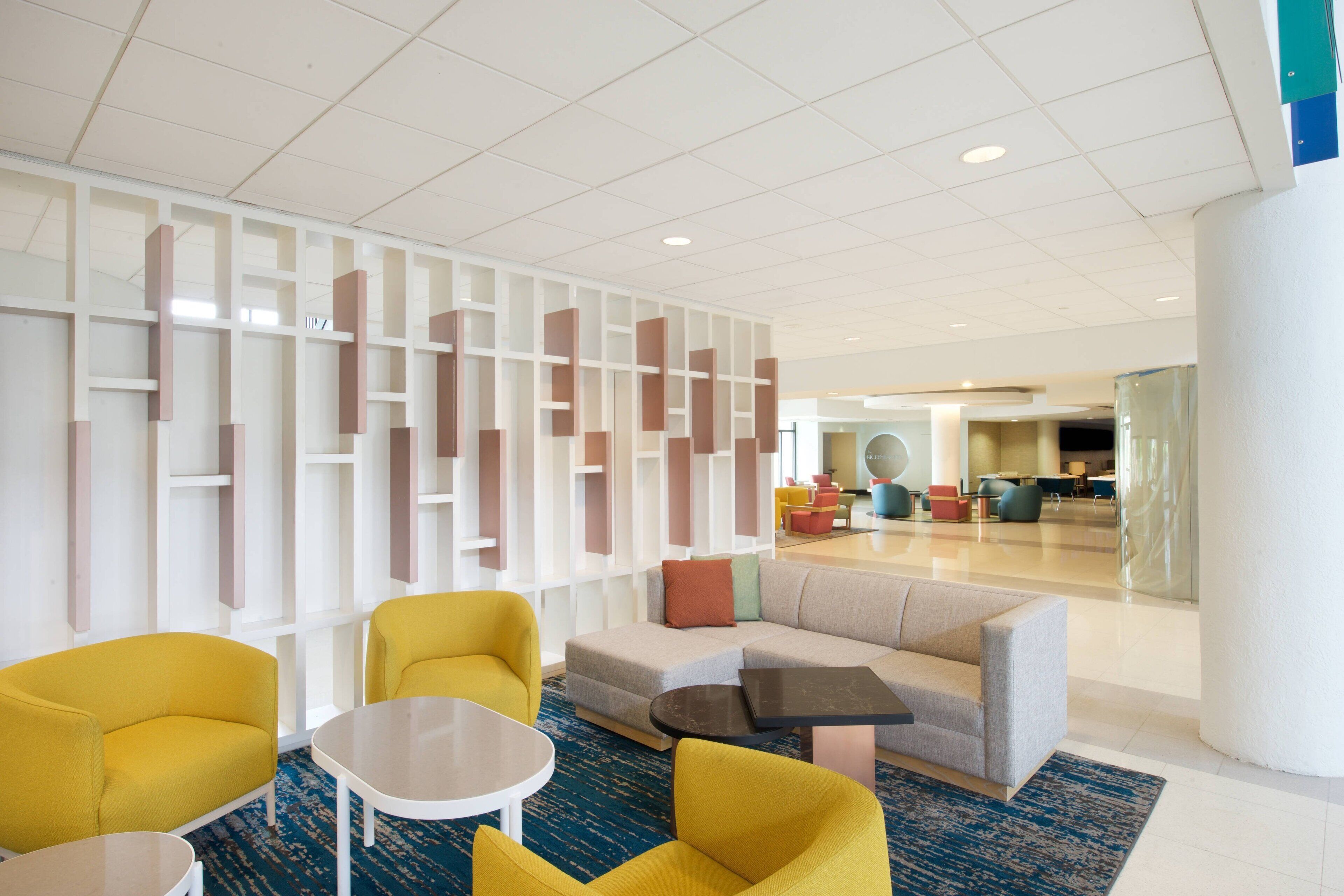 A modern lobby with a sectional sofa, yellow armchairs, and a coffee table.