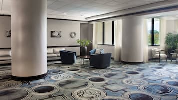 Eine moderne Lobby mit einem gemusterten Teppich, Sitzbereichen und großen Fenstern.
