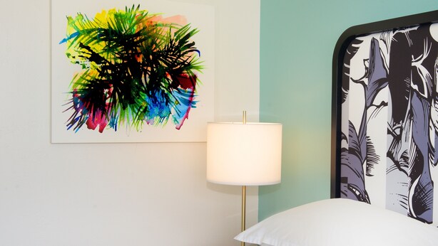 A hotel room with a bed, a nightstand with a lamp, and a colorful abstract painting on the wall. - Sheraton Miami Airport Hotel & Executive Meeting Center (Miami)