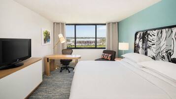 A hotel room with a bed, a desk, a television, and a window with a view.