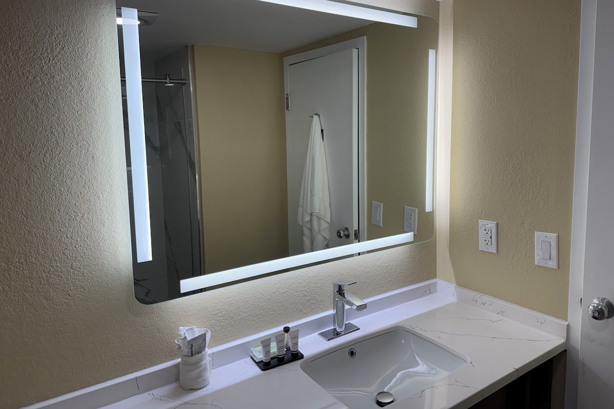 A bathroom with a large mirror, a white sink, and a towel rack.