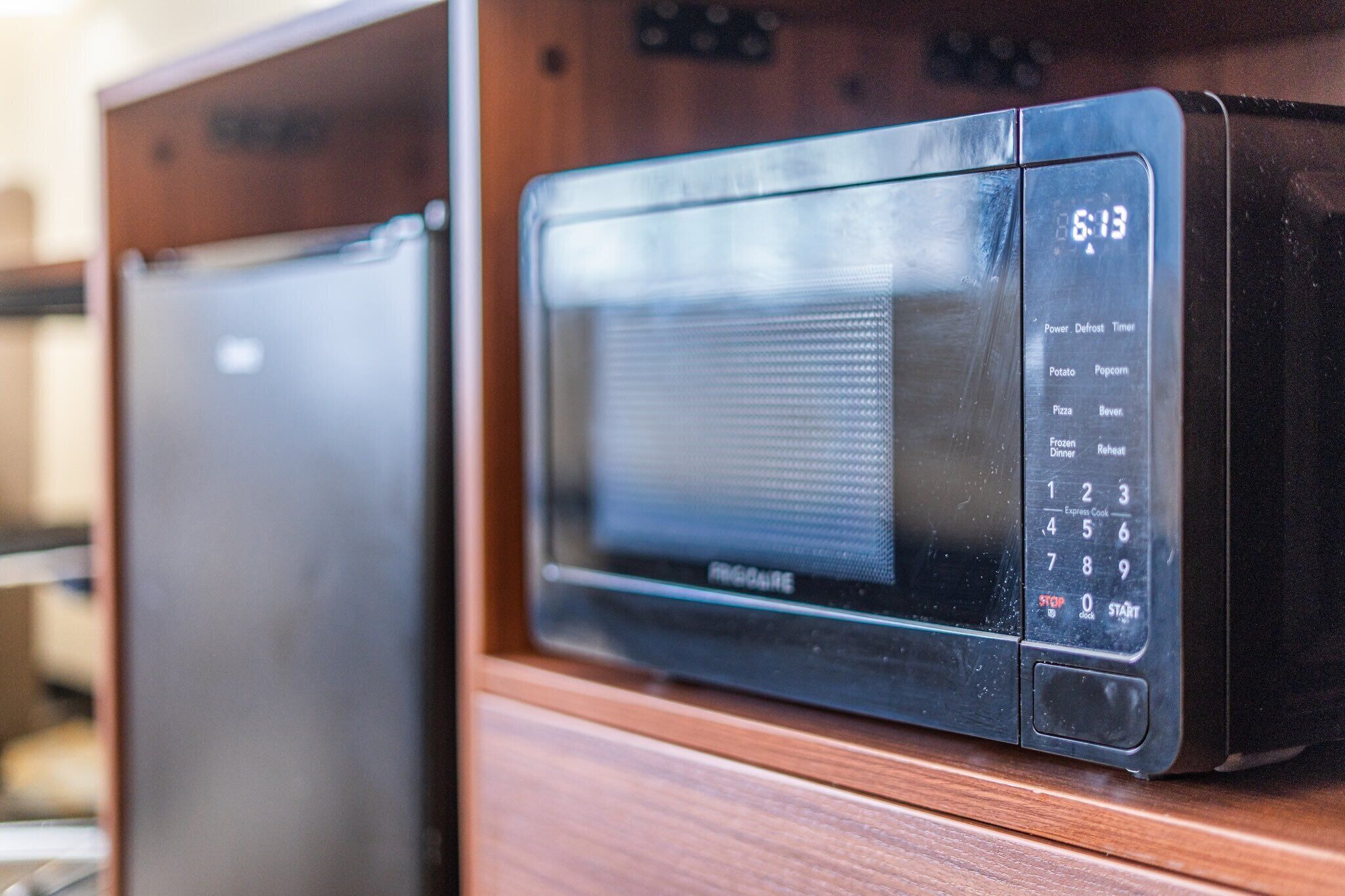 Un horno microondas con pantalla digital y panel de control, sobre una superficie de madera.