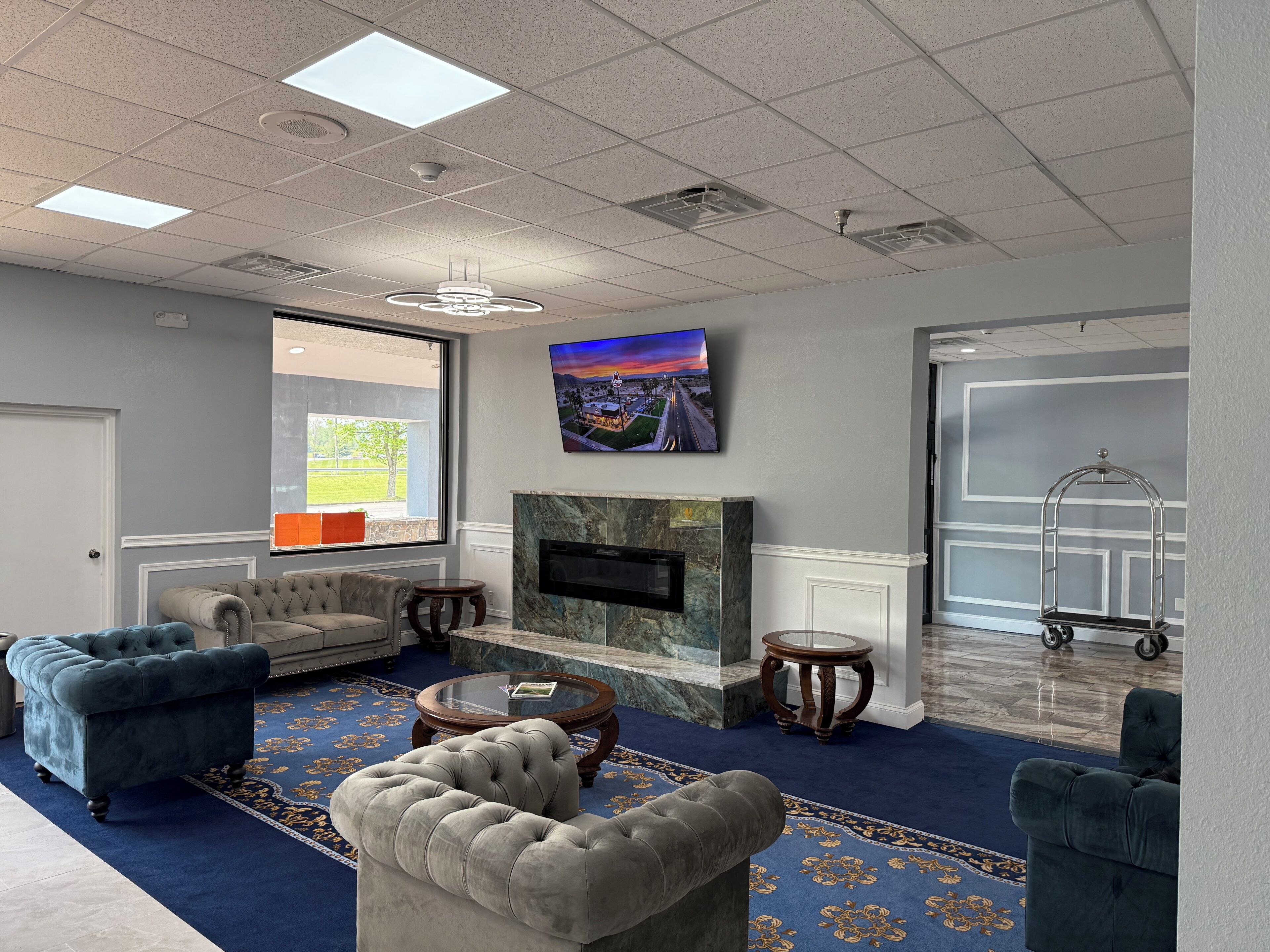 A hotel lobby with a fireplace, seating area, and a large window.