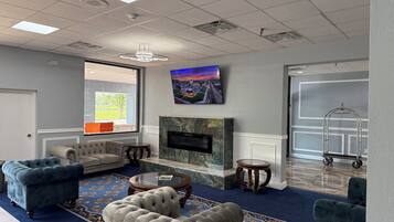 A hotel lobby with a fireplace, seating area, and a large window.
