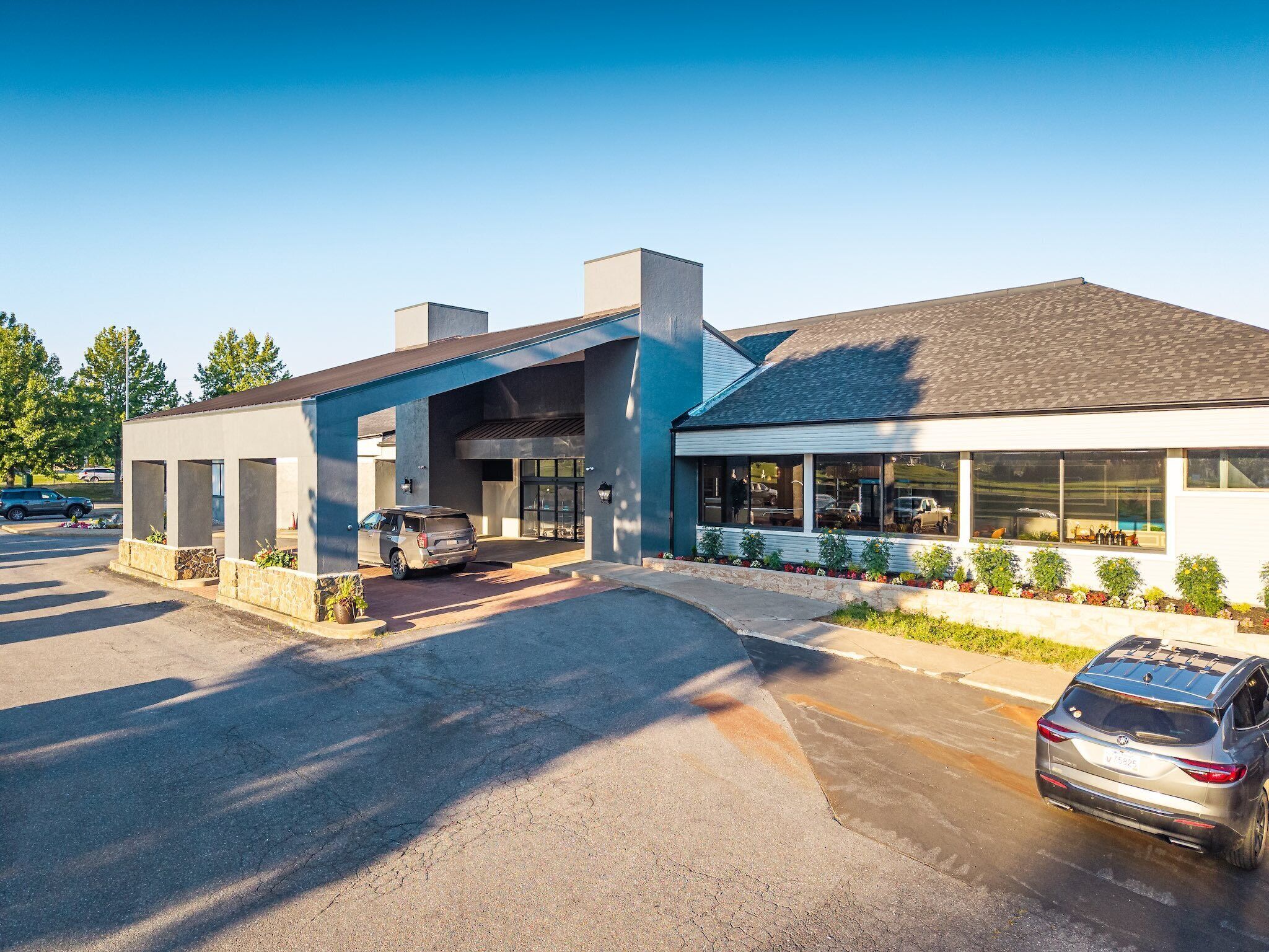 A modern building with a covered parking area, a garage, and a large windowed storefront.