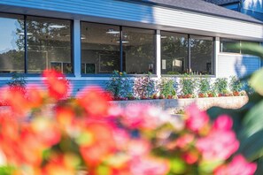 A modern building with large windows and a well-maintained garden with colorful flowers. - Holiday Lodge Hotel & Conference Center (Oak Hill)