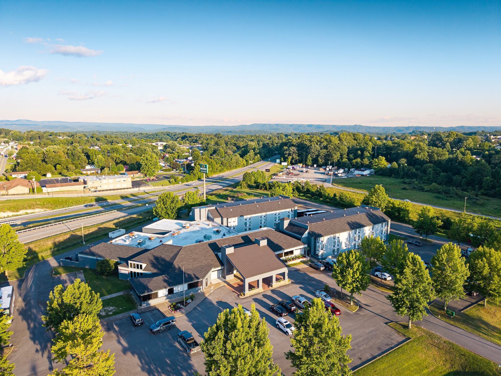 A multi-story hotel with a parking lot and a view of the surrounding area.
