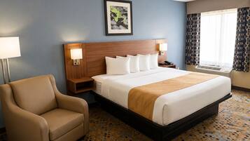 A hotel room with a bed, bedside tables, a chair, a picture on the wall, and a window with curtains.