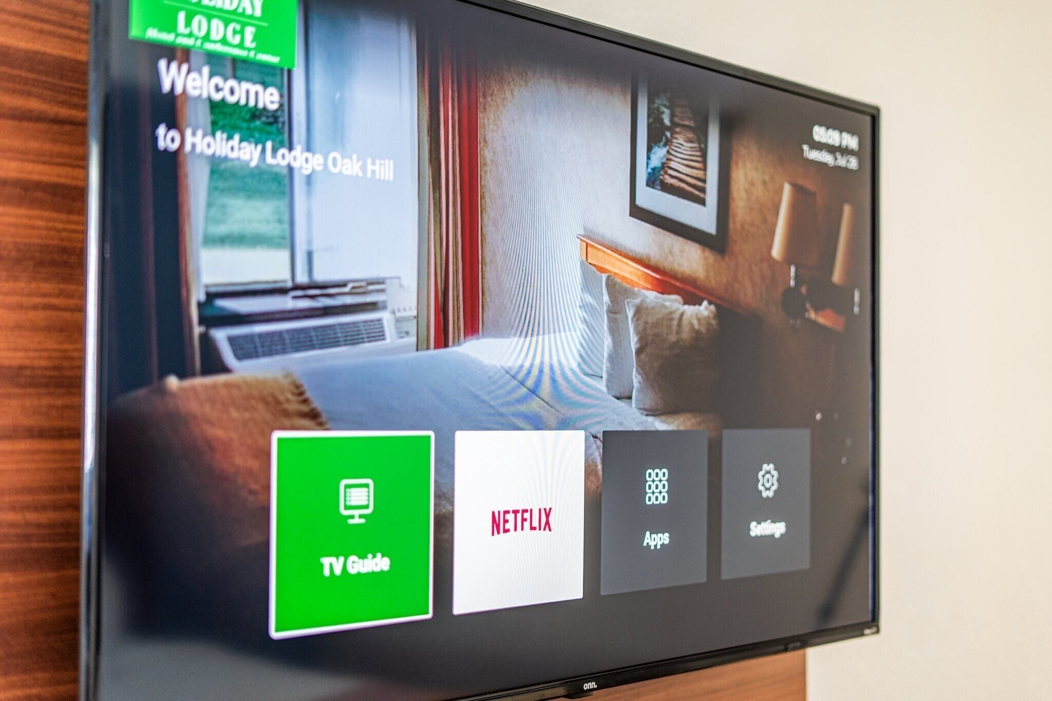 Ein Fernsehbildschirm zeigt eine Willkommensnachricht für Holiday Lodge Oak Hill mit Menüoptionen für TV-Guide, Netflix und Einstellungen.