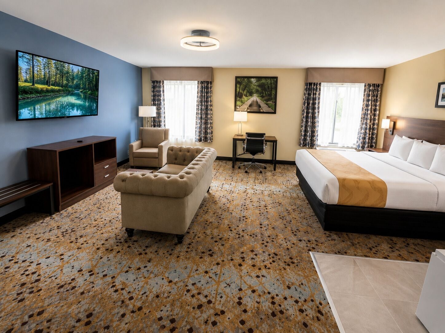 Quarto de hotel com cama, sofá, escrivaninha e televisão.