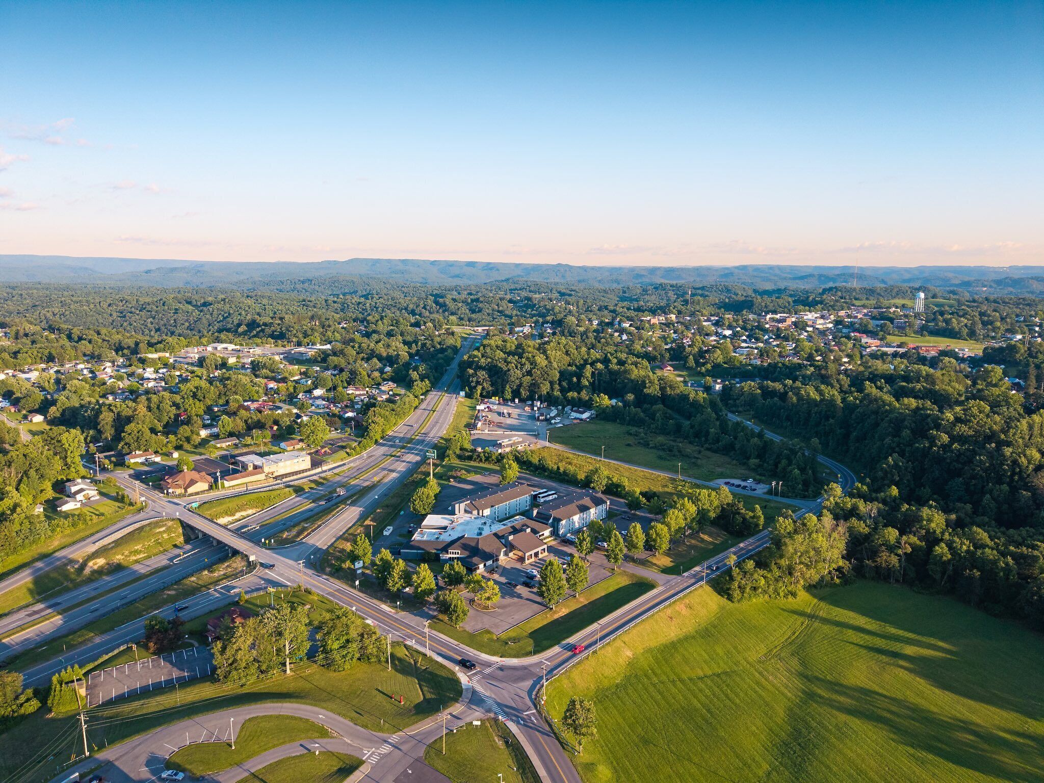 An aerial view of a town with a central roundabout, surrounding roads, and a mix of residential and commercial buildings.