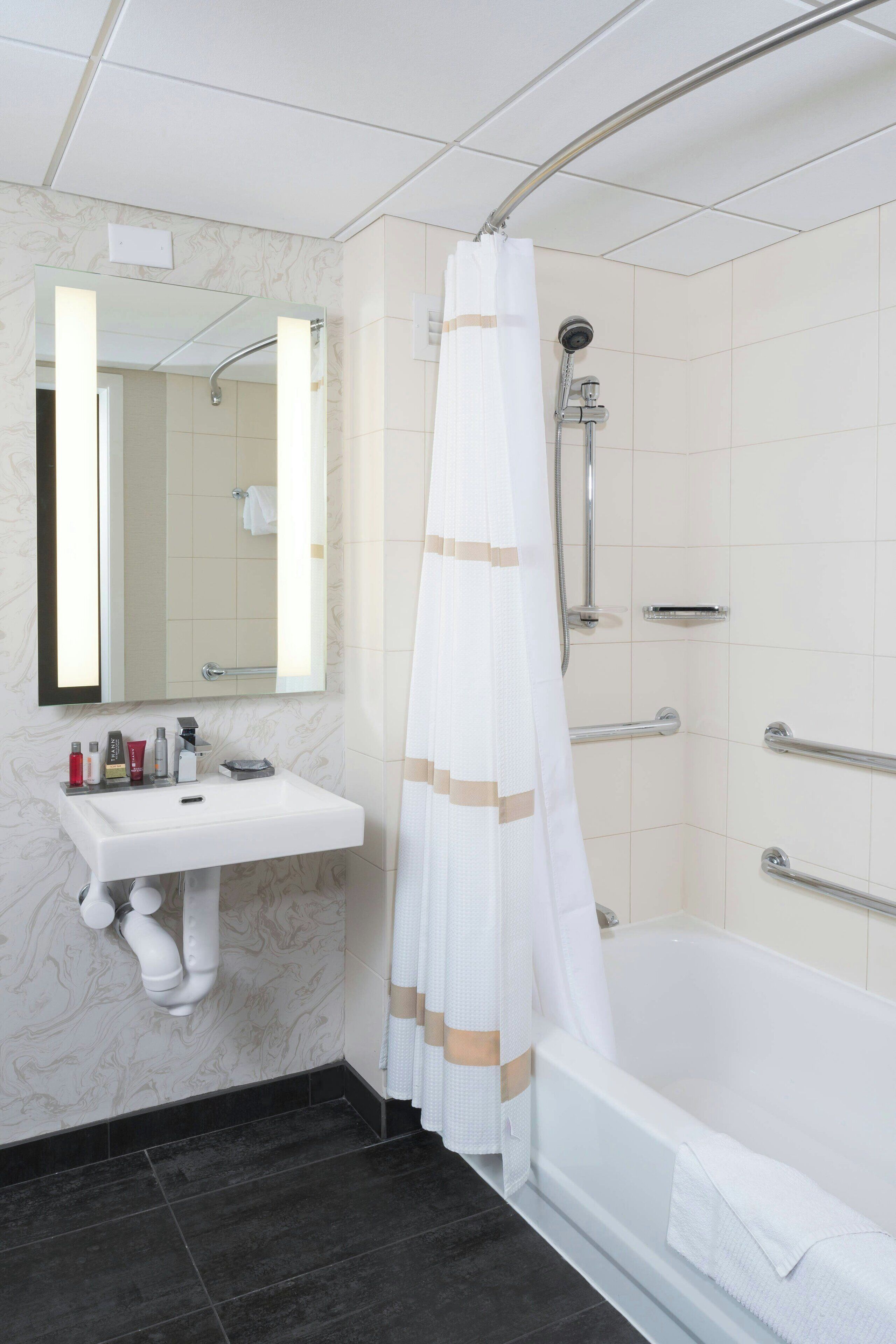 A bathroom with a white sink, mirror, shower, and bathtub.