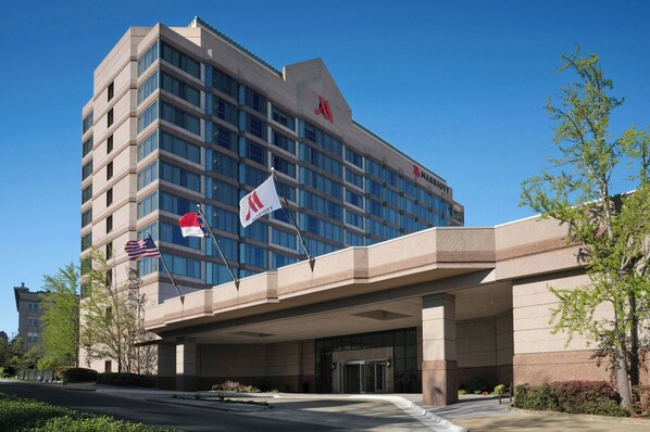 A multi-story hotel with a prominent 'Marriott' sign, a flagpole with flags, and a covered entrance. - Durham Marriott City Center (Durham)
