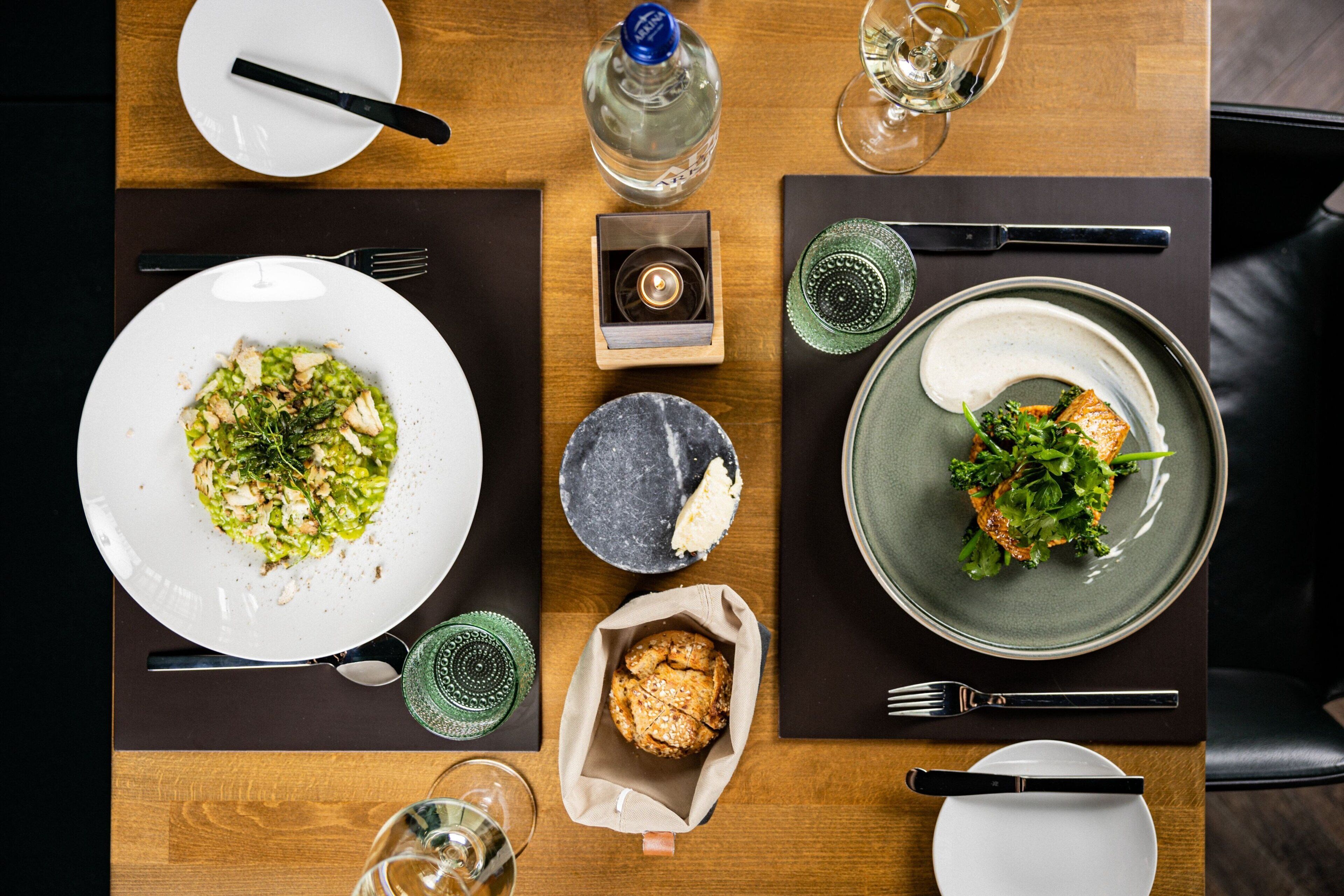 A dining table with plates of food, cutlery, and glasses.