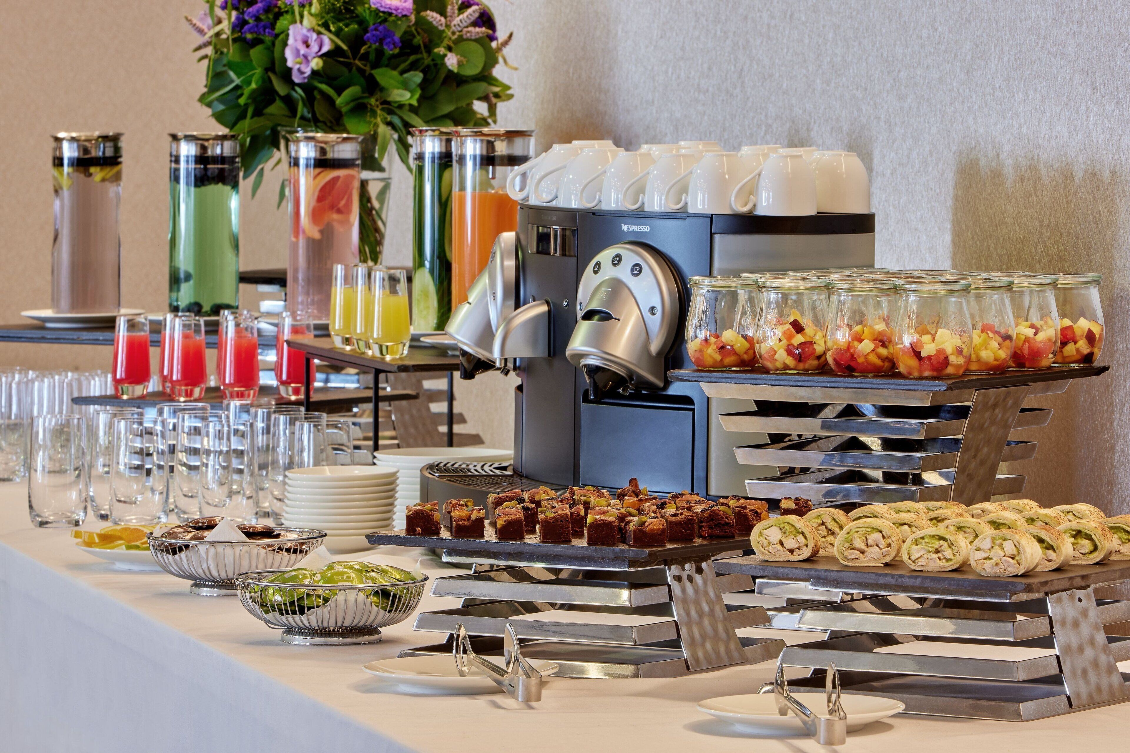 A buffet with various food items, a coffee machine, and beverage dispensers.