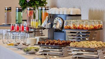 Un bufé con diferentes opciones de comida, una máquina de café y dispensadores de bebidas.