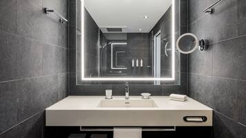 Une salle de bain moderne avec un grand miroir, un lavabo blanc et un porte-serviettes.