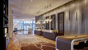 Un moderno vestíbulo de hotel con mostrador de recepción, zona de estar y una alfombra grande con diseño.