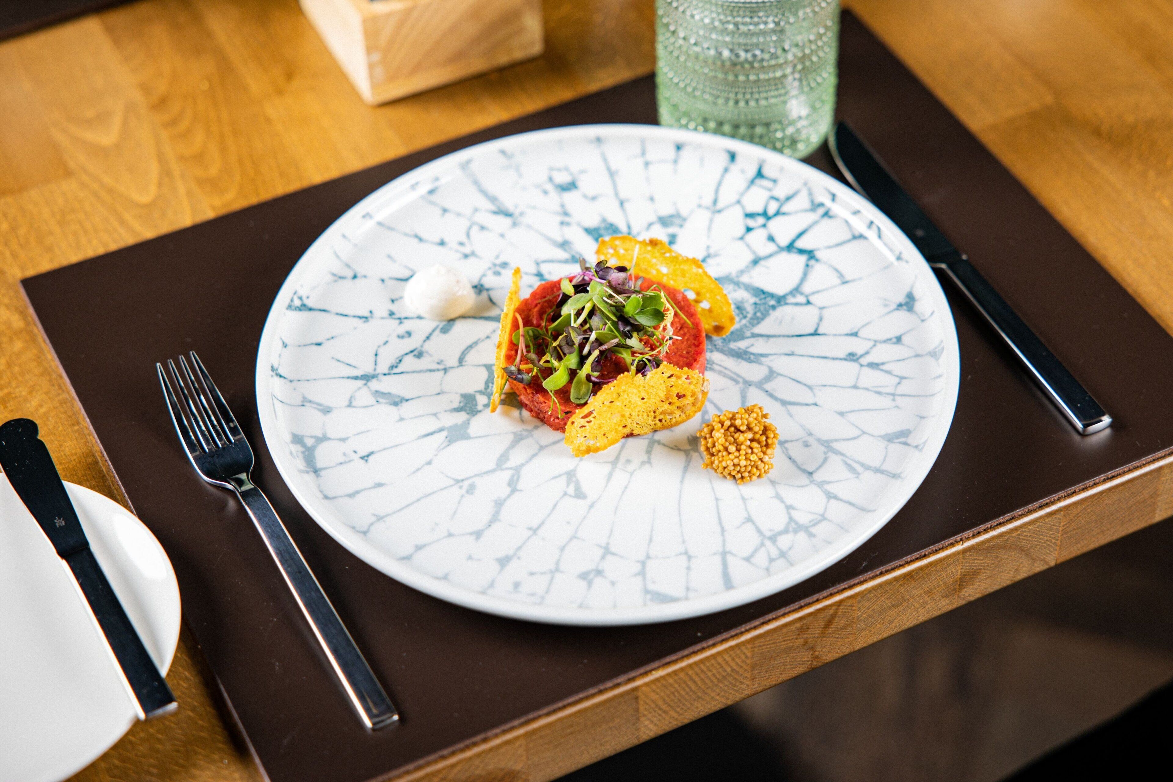A plate of food on a wooden table with a fork and knife to the left.