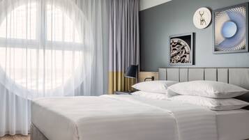 Ein modernes Hotelzimmer mit einem großen Bett, einem Nachttisch, einer Lampe und einem Kunstwerk an der Wand.