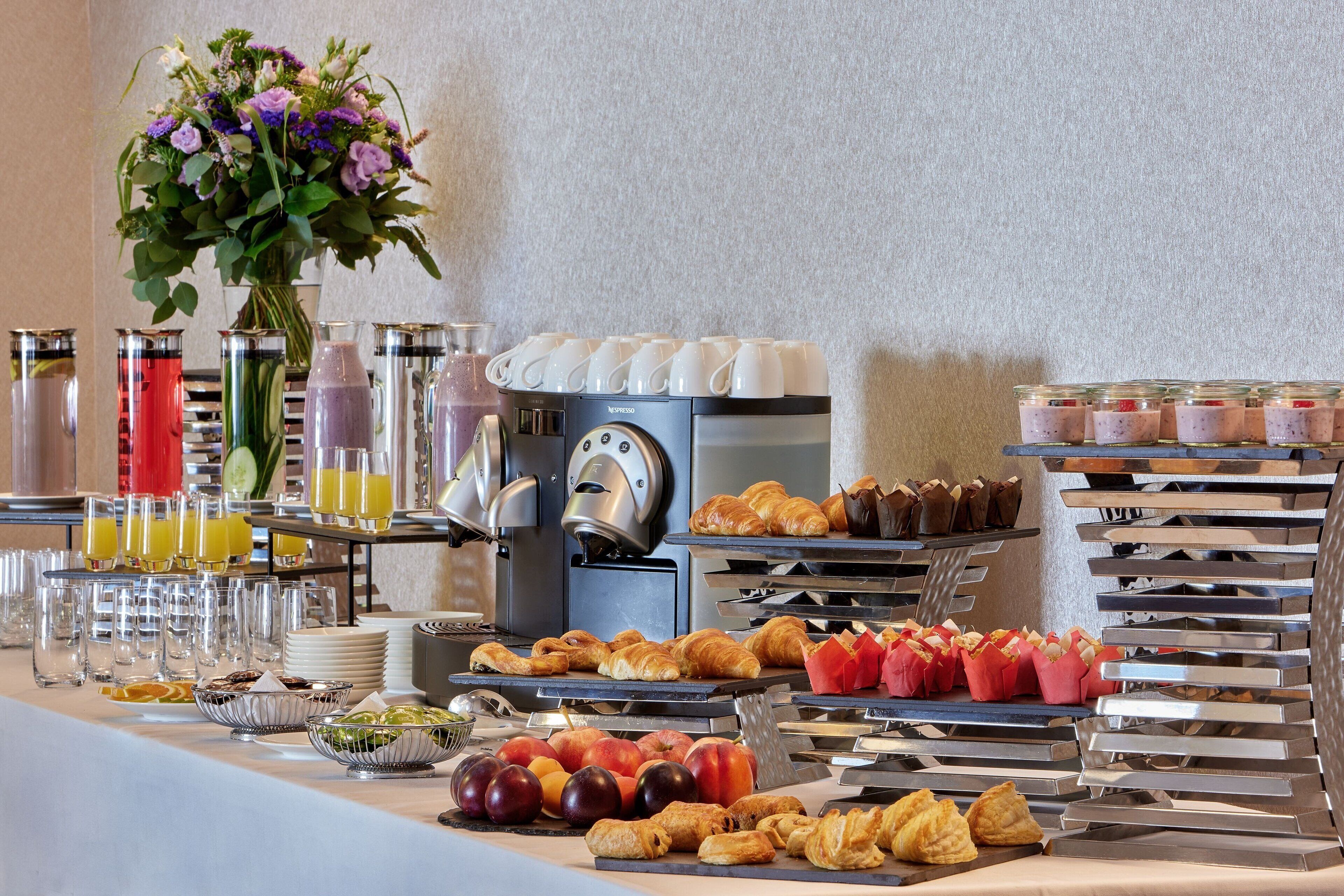 A buffet setup with various food items, beverages, and a coffee machine.
