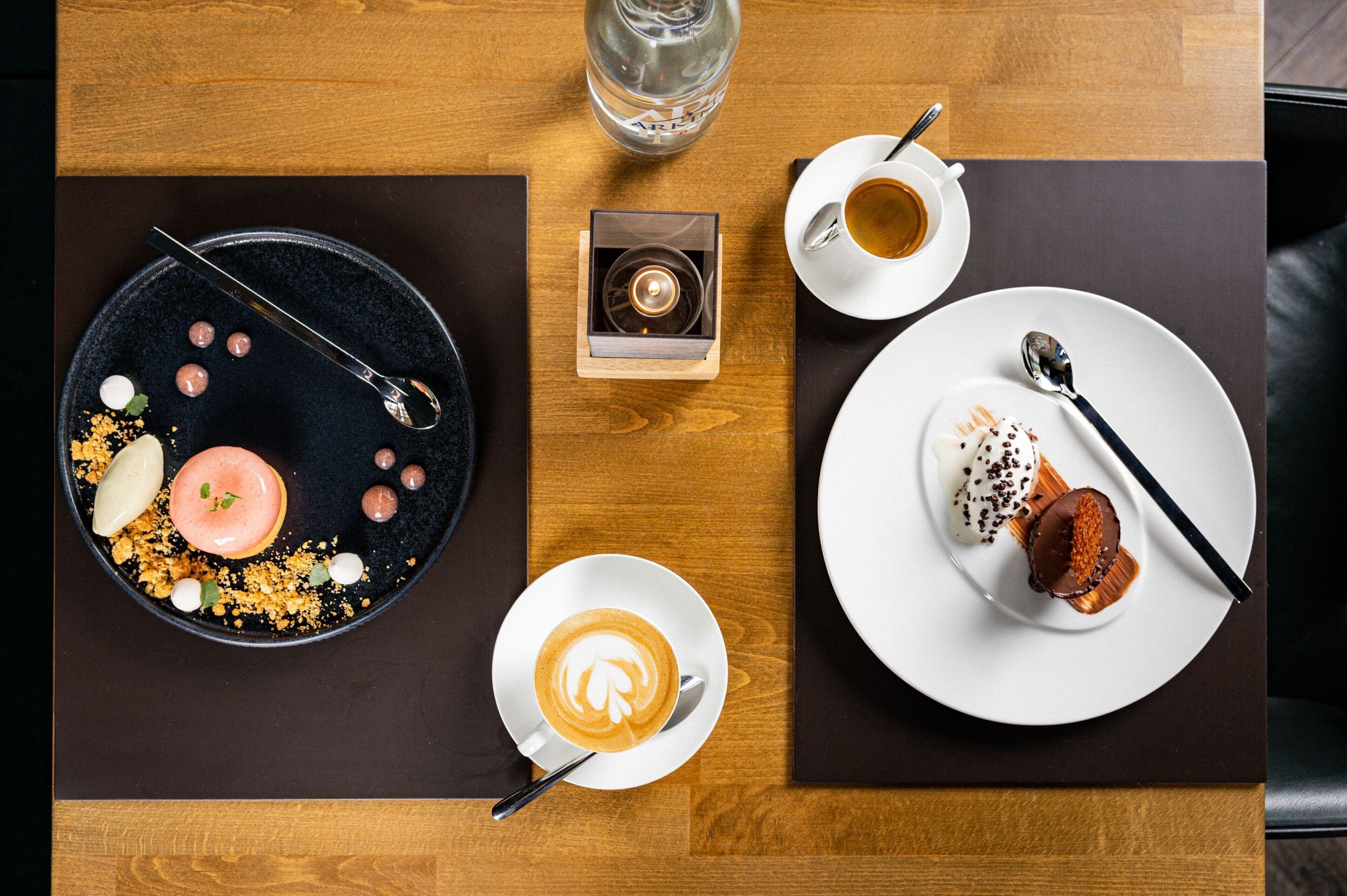 A table with a dessert plate, a cup of coffee, and a small box of chocolate.