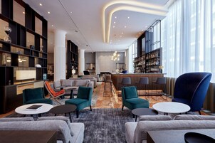 Un moderno vest íbulo de hotel con un bar, zonas de estar y un gran ventanal.