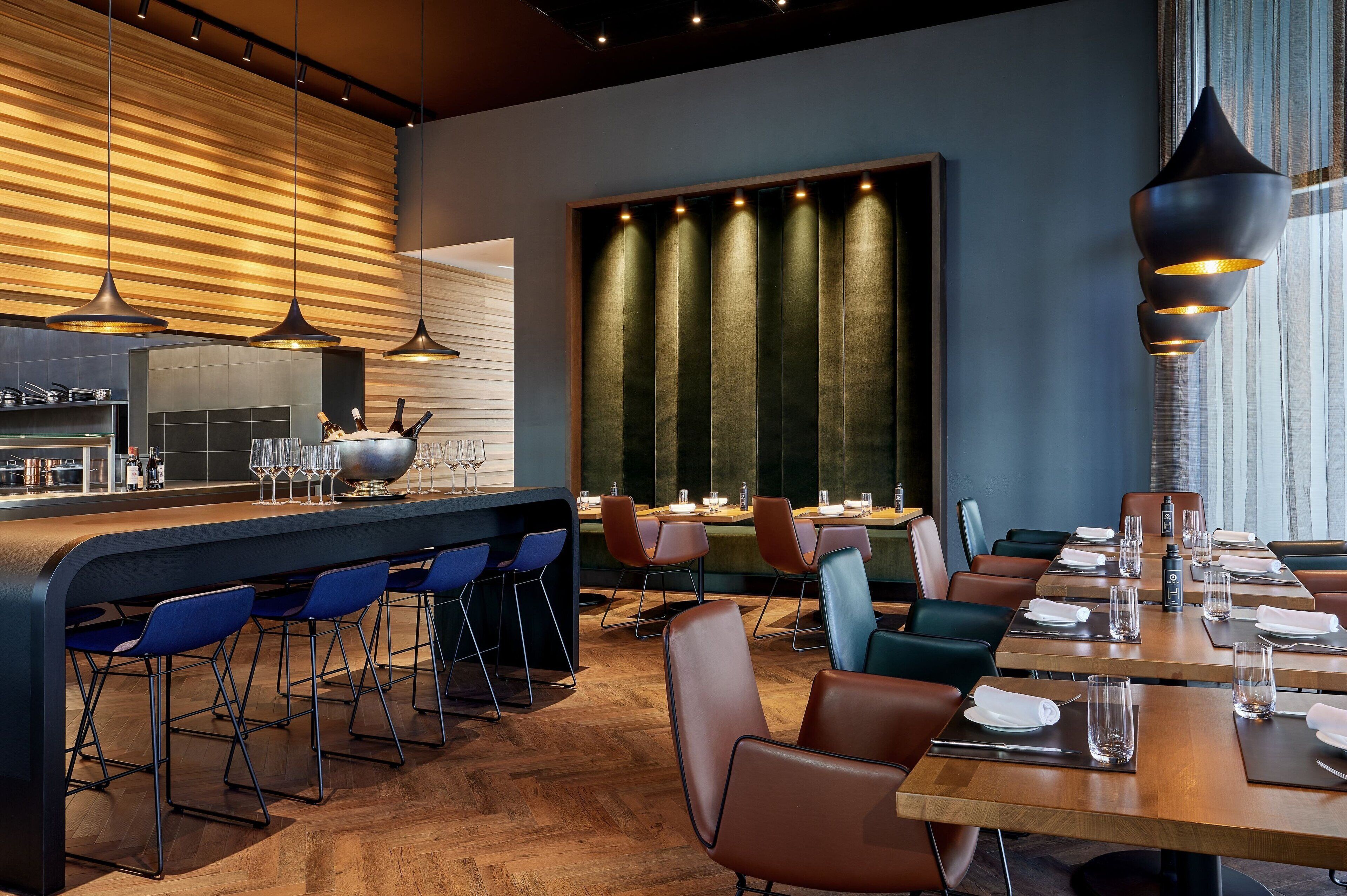 Un restaurant moderne doté d’un bar, de planchers en bois et d’un agencement varié des sièges, comprenant des tabourets de bar et des tables avec des chaises.